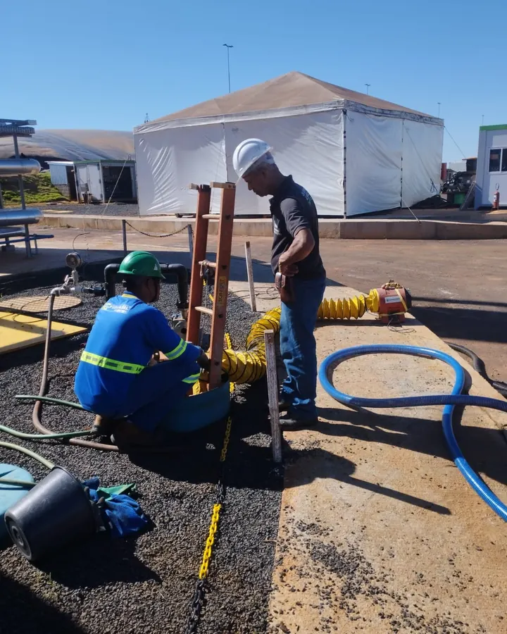 Equipe de capacete e colete trabalhando em tubulação externa