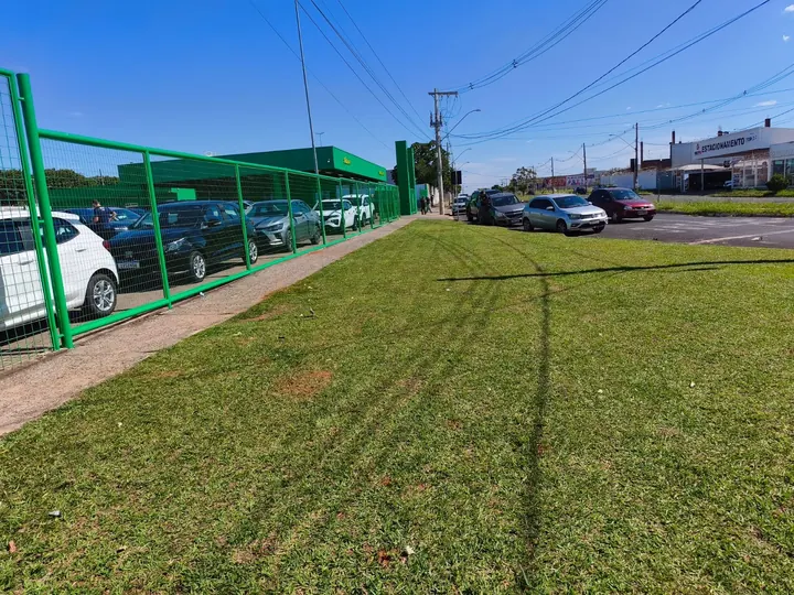 Gramado extenso recém-roçado ao lado de estacionamento